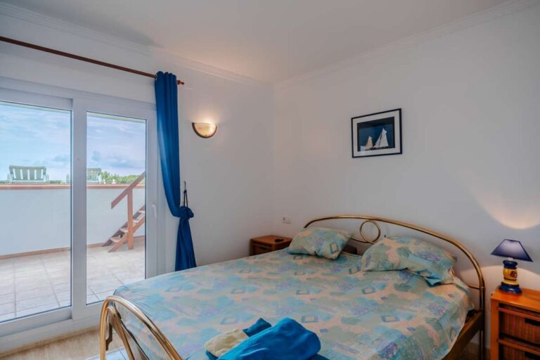 Bedroom inside a duplex apartment near Les Platgetes Beach in Moraira with double bed, terrace access, sea views and bright interior finish