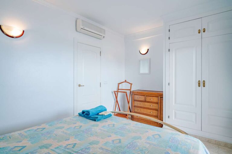 Bedroom inside a duplex apartment near Les Platgetes Beach in Moraira with fitted storage, air conditioning, double bed and bright white interior