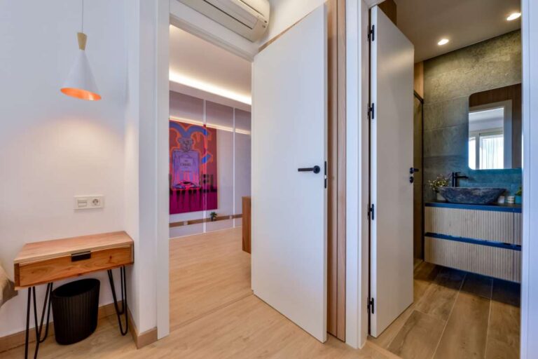 Bedroom inside a luxury frontline beach duplex in Mascarat, Altea with bathroom access, fitted storage, modern lighting and wood-effect flooring