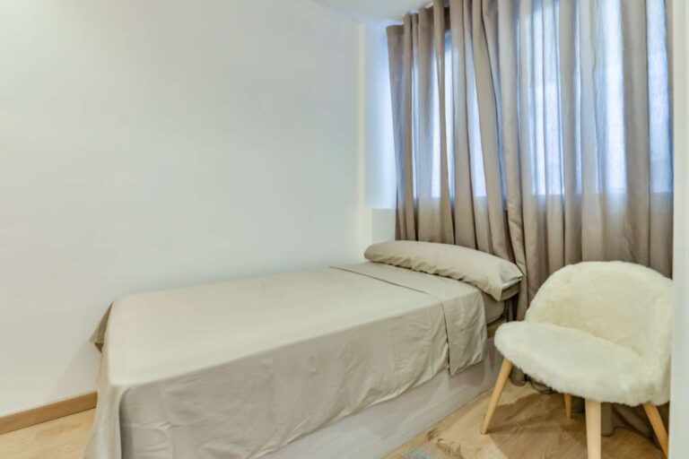 Bedroom inside a luxury frontline beach duplex in Mascarat, Altea with double bed, armchair, curtains and neutral modern interior