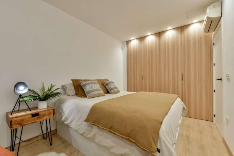 Bedroom inside a luxury frontline beach duplex in Mascarat, Altea with fitted storage, double bed, bedside table and warm neutral styling