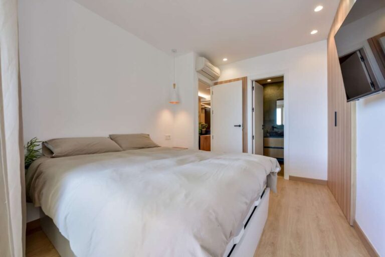 Bedroom inside a luxury frontline beach duplex in Mascarat, Altea with hallway access, double bed, modern lighting and neutral interior finish