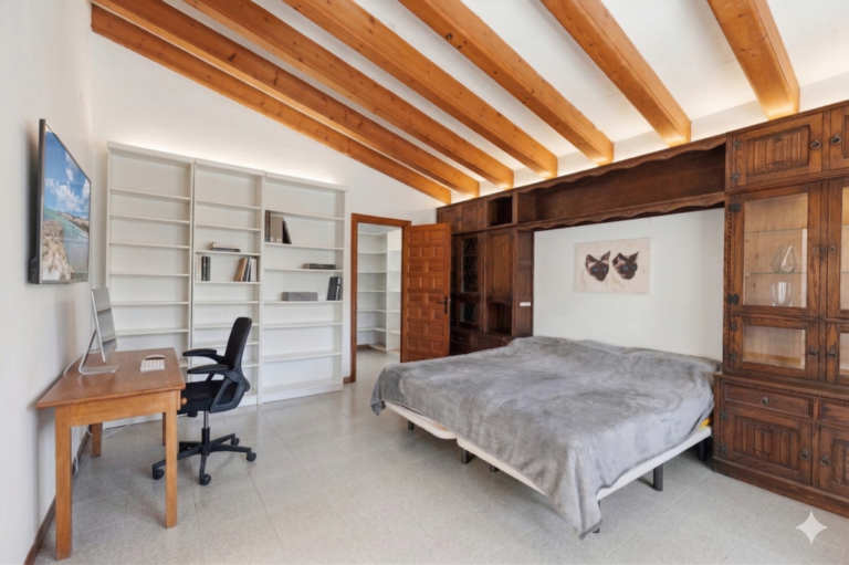 Bedroom inside a Mediterranean villa in Benissa Costa with wooden fitted storage, study desk, shelving and exposed ceiling beams