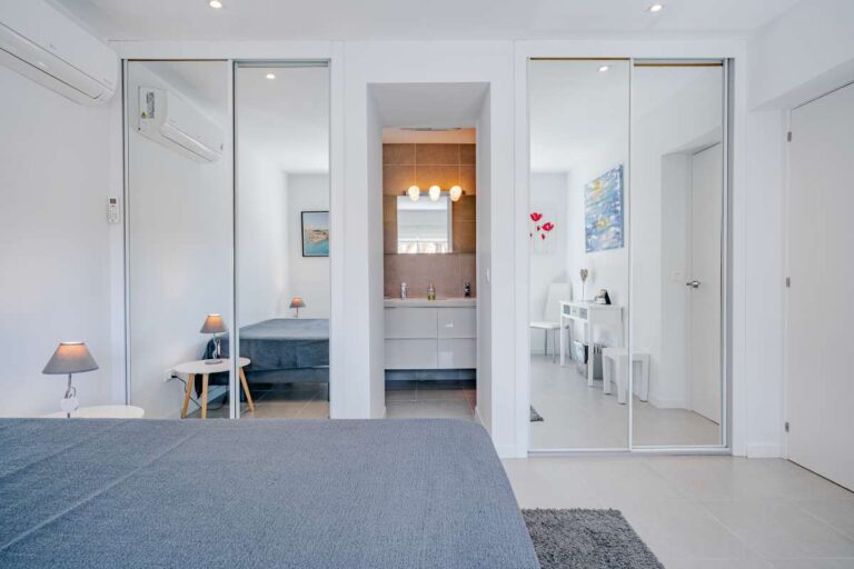 Bedroom inside a modern Calpe villa with fitted wardrobes, large mirror doors and access to an en-suite bathroom