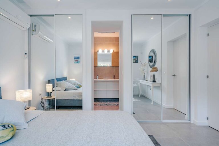 Bedroom inside a modern Calpe villa with fitted wardrobes, mirror doors and access to an en-suite bathroom