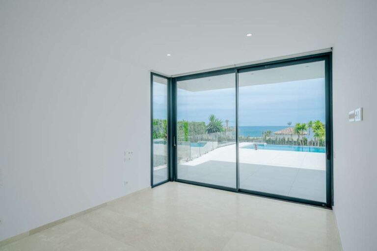 Bedroom inside a modern villa in La Calalga, Calpe with floor-to-ceiling glass doors, pool views and Mediterranean Sea views
