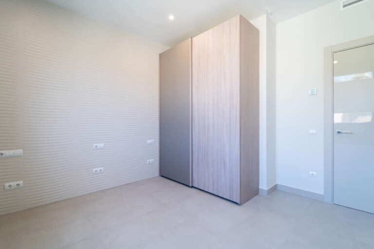 Schlafzimmer in einer neu gebauten Luxusvilla in der Nähe des Yachthafens Puerto Blanco in Calpe mit Einbauschrank, moderner Tür und hellem, neutralem Interieur