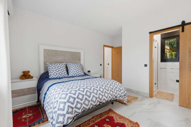 Bedroom inside a premium coastal villa on the Benissa Costa with patterned bedding, en-suite access and bright modern interior