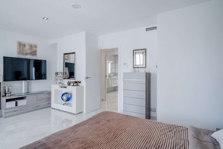 Bedroom inside a renovated Arenal-Bol apartment in Calpe with TV area, storage units and bright modern finish