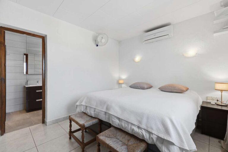 Bedroom inside a renovated single-level villa in Moraira with en-suite access, air conditioning, bright neutral finish and modern bathroom nearby