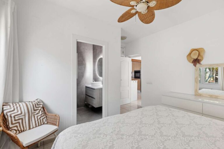 Bedroom inside a renovated single-level villa in Moraira with en-suite access, ceiling fan, neutral interior and bright Mediterranean finish
