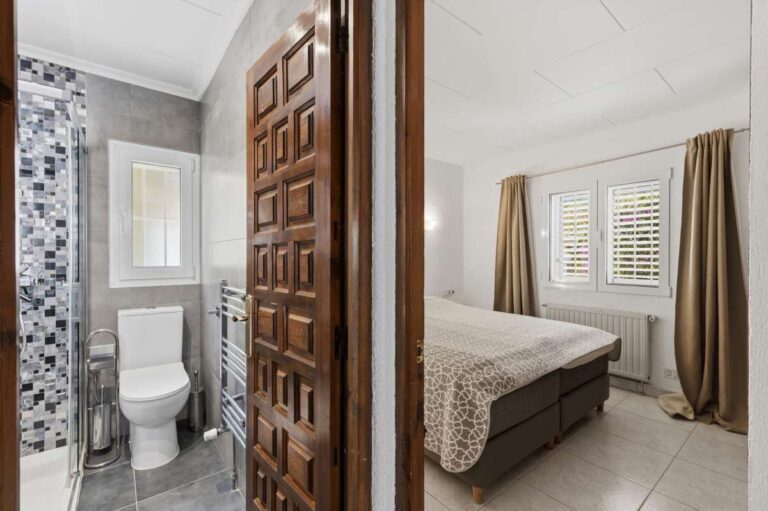 Bedroom inside a renovated single-level villa in Moraira with en-suite access, shutters, neutral interior and modern shower room nearby