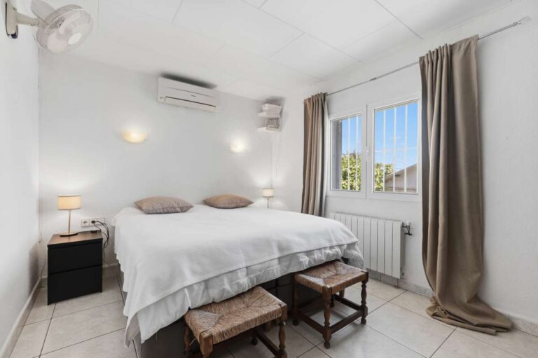 Bedroom inside a renovated single-level villa in Moraira with garden views, air conditioning, radiator and bright neutral interior