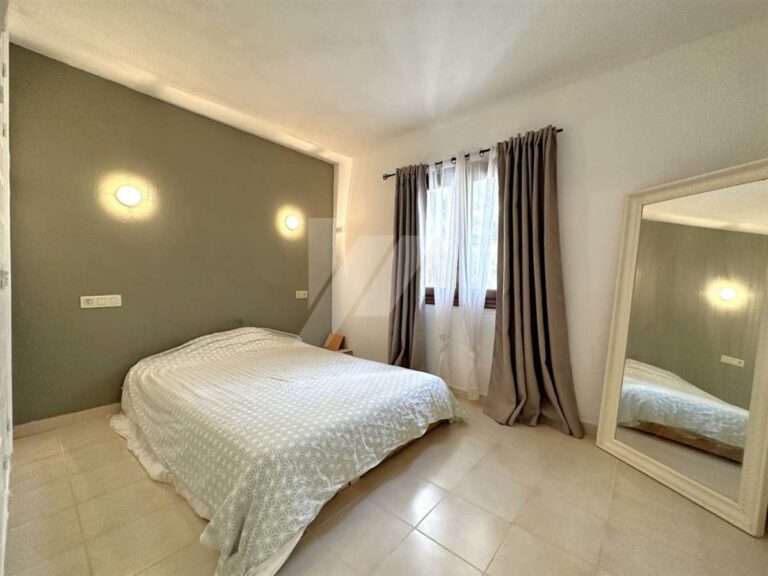 Bedroom inside a single-level villa near El Portet Beach in Moraira with double bed, fitted storage, tiled floor and natural light