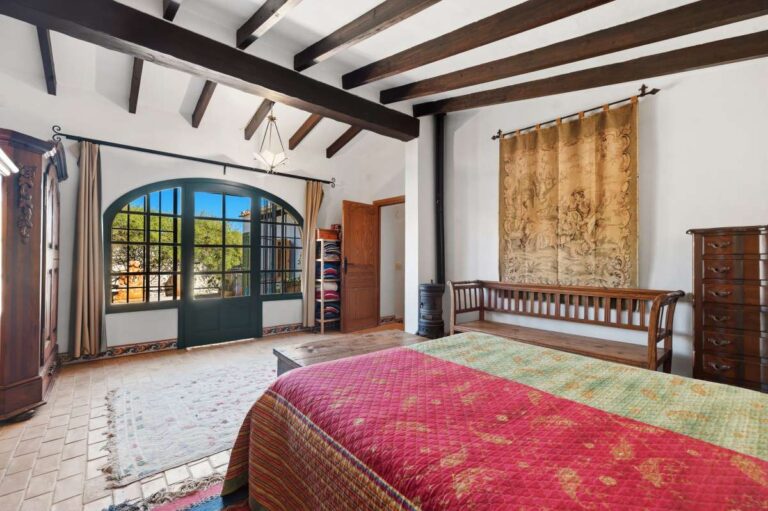 Bedroom inside a traditional Spanish finca near Moraira with arched doors, beamed ceiling, wooden furniture and rustic Mediterranean interior