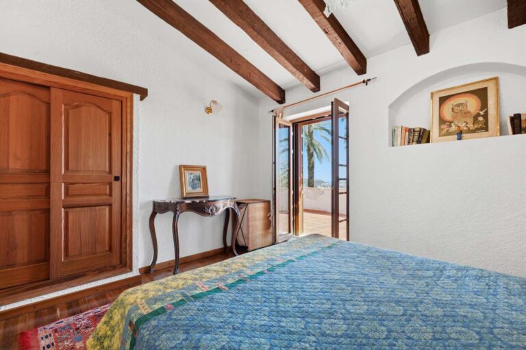 Bedroom inside a traditional Spanish finca near Moraira with wooden wardrobe, beamed ceiling, terrace access and rustic Mediterranean interior