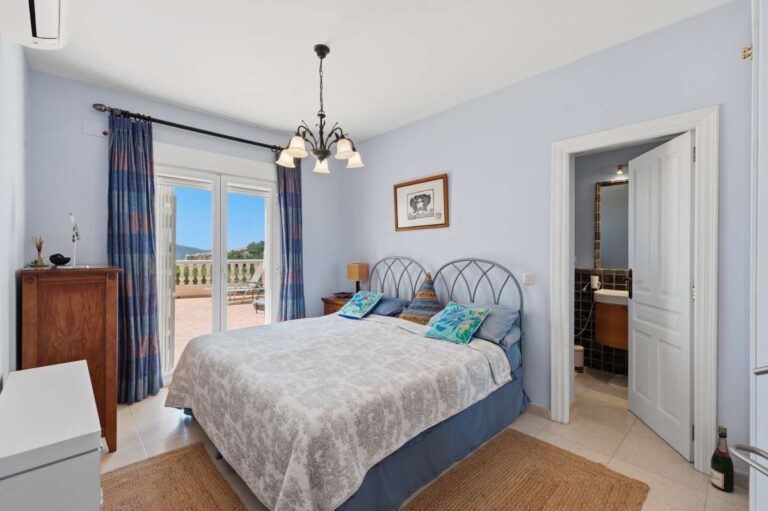 Bedroom inside an elegant Mediterranean villa in Altea Hills with terrace access, en-suite bathroom, blue curtains and bright Mediterranean interior