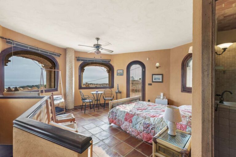 Bedroom suite inside a finca-style villa in Benissa Costa with sea views, arched windows, sitting area and rustic Mediterranean details
