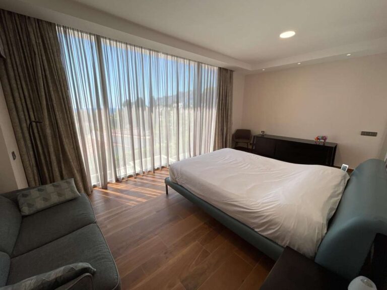 Bedroom suite inside a modern luxury villa in La Calalga, Calpe with seating area, wooden flooring, fitted curtains and bright interior finish