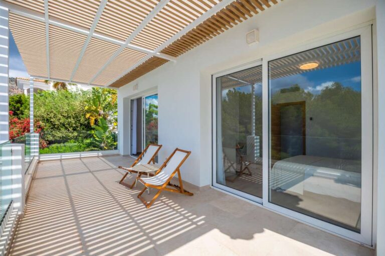 Bedroom terrace access at a modern villa in Altea Hills with shaded terrace, glass railing, sun loungers and bright exterior finish
