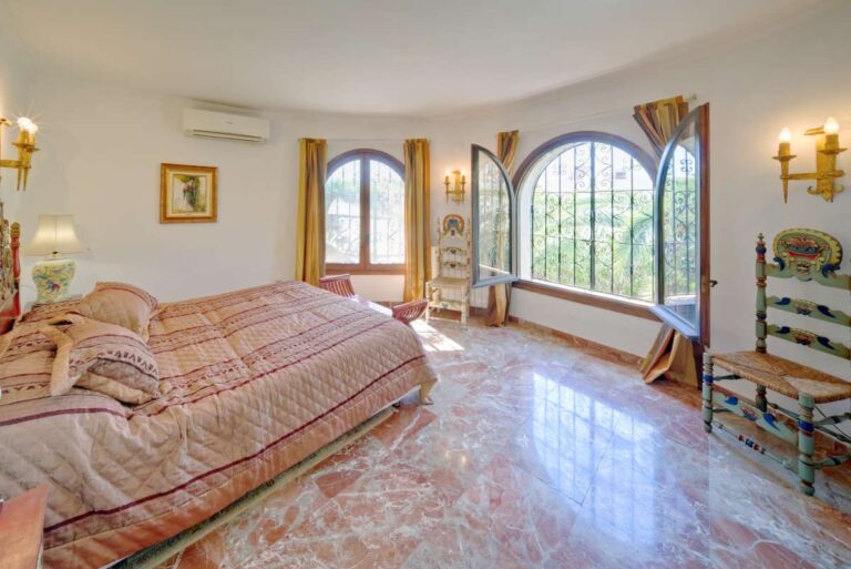 Bedroom with arched windows, traditional furniture and natural light inside a second line Mediterranean villa near Puerto Blanco in Calpe.