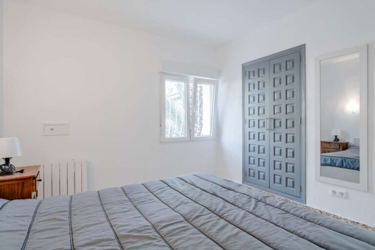 Bedroom with blue door, natural light and tiled flooring inside a Mediterranean villa in Maryvilla, Calpe.