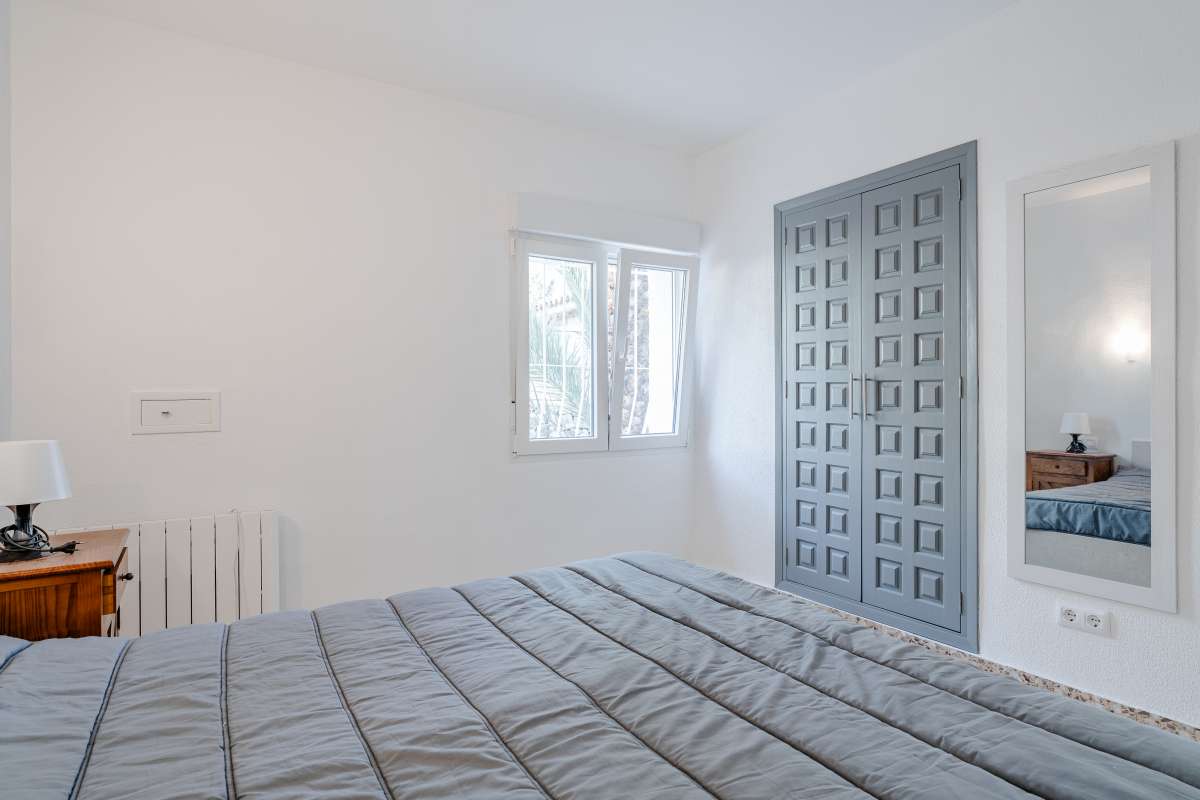Bedroom with blue door, natural light and tiled flooring inside a Mediterranean villa in Maryvilla, Calpe.