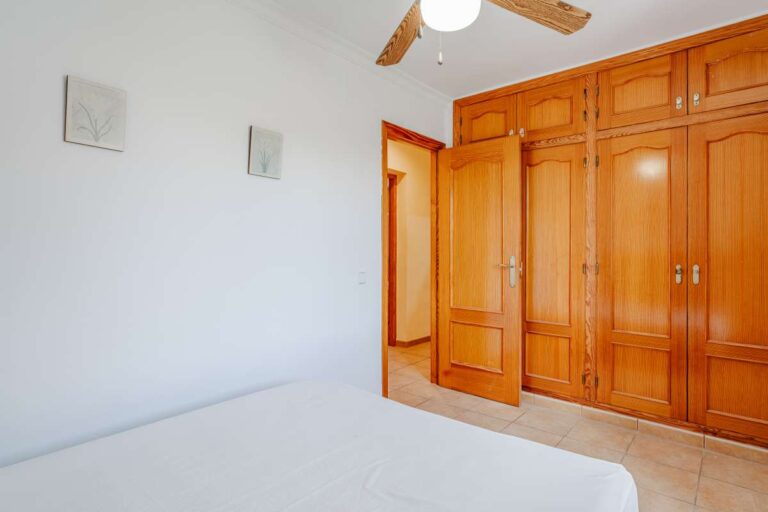 Bedroom with built-in wooden wardrobes and ceiling fan inside a Mediterranean villa with guest accommodation in Calpe.