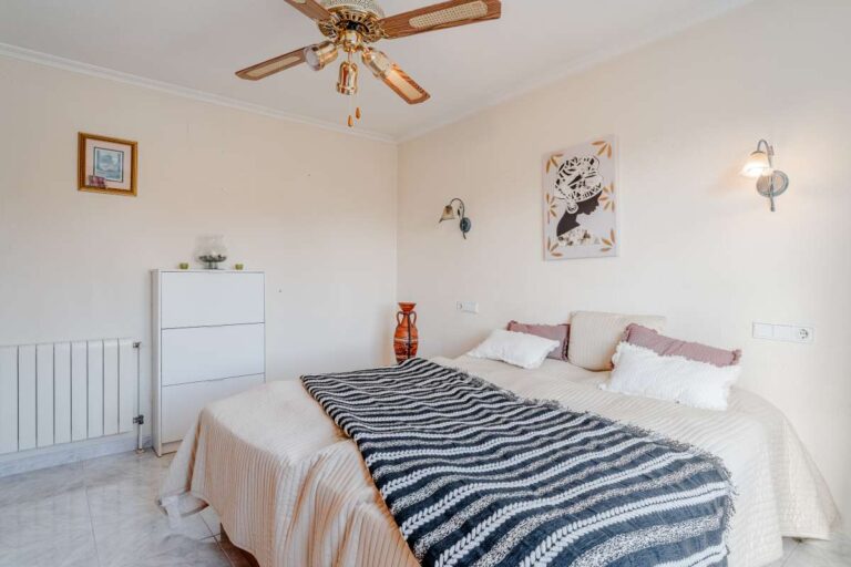 Bedroom with ceiling fan, radiator and traditional furniture inside a Mediterranean villa with independent guest accommodation in Calpe.