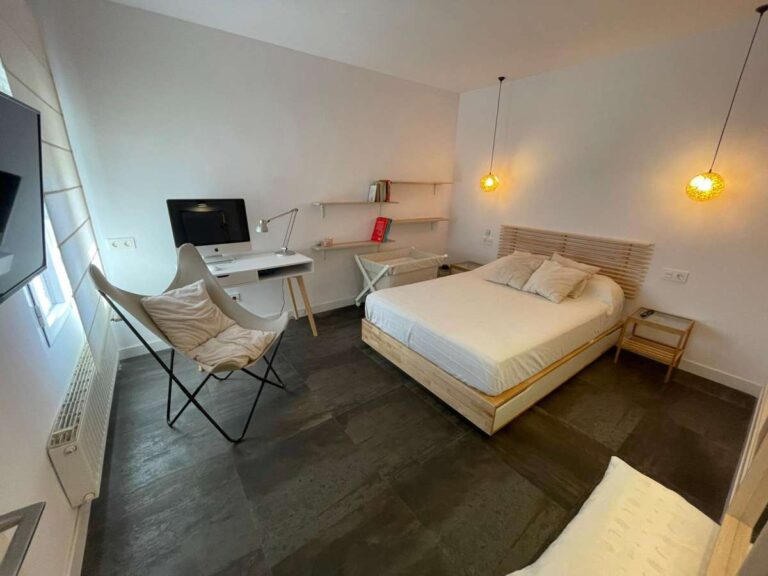 Bedroom with desk area, pendant lighting and natural light inside a refurbished villa with three independent apartments in Canuta, Calpe.