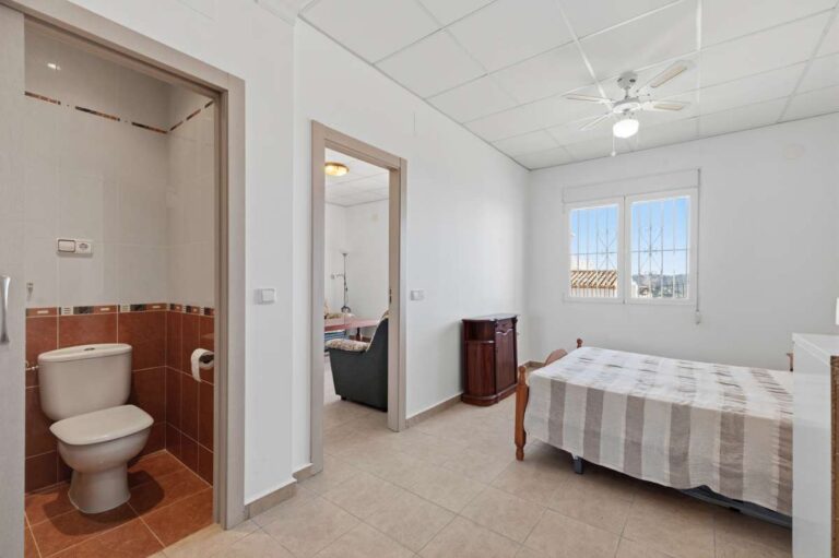 Bedroom with direct bathroom access and natural light inside a villa in Calpe.