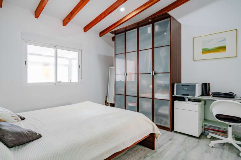 Bedroom with fitted storage, workspace and exposed ceiling beams inside a renovated Mediterranean villa in La Cometa, Calpe.