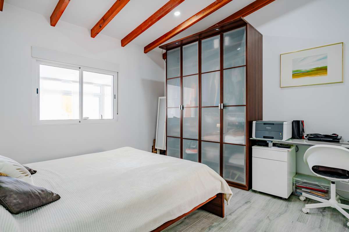 Bedroom with fitted storage, workspace and exposed ceiling beams inside a renovated Mediterranean villa in La Cometa, Calpe.