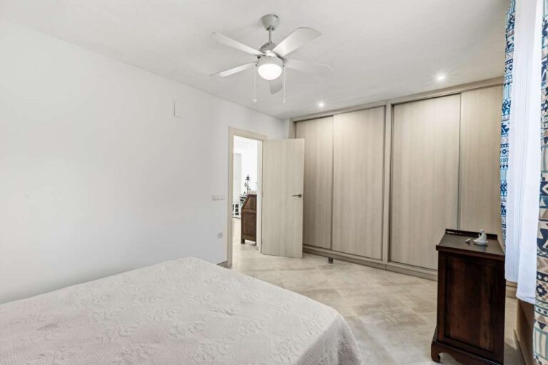 Bedroom with fitted wardrobes, ceiling fan and natural light inside a contemporary villa in Calpe.