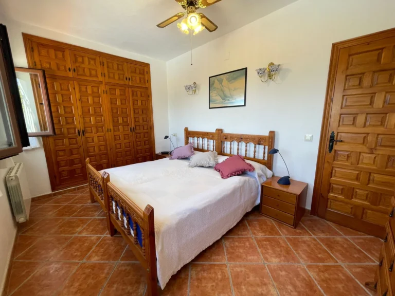 Bedroom with fitted wardrobes, tiled floor, and natural light inside a villa in Calpe.