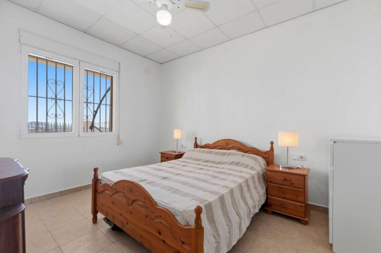 Bedroom with natural light, bedside tables, and fitted window inside a villa in Calpe.