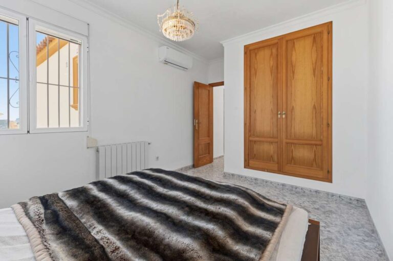Bedroom with natural light, radiator, and wooden door inside a villa in Calpe.