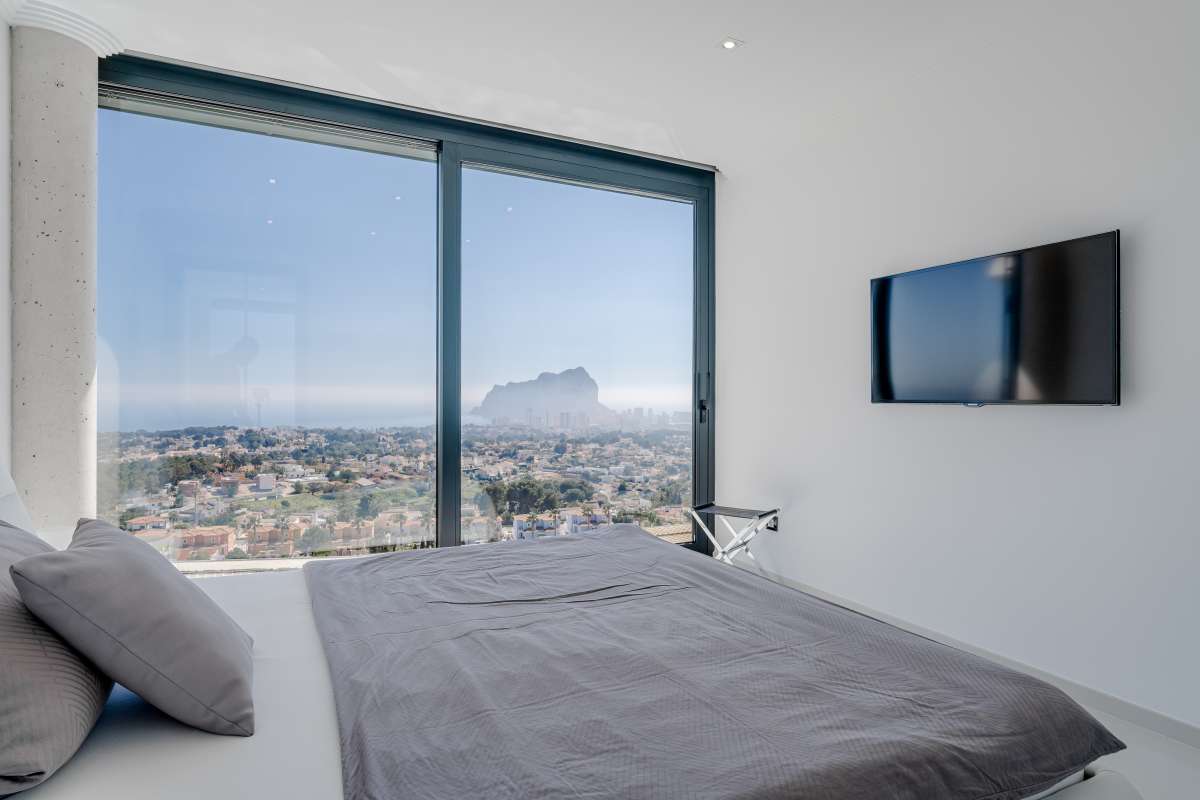Bedroom with panoramic sea views, white interior finishes and wall-mounted TV inside a luxury villa in Gran Sol, Calpe.