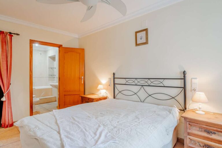 Bedroom with traditional furniture and en-suite bathroom access inside a Mediterranean villa with guest accommodation in Calpe.