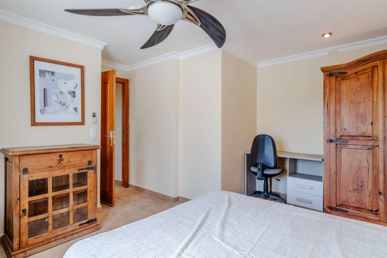 Bedroom with traditional furniture, desk area and ceiling fan inside a Mediterranean villa with independent guest accommodation in Calpe.