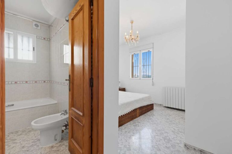 Bedroom with wooden door and access towards the bathroom inside a villa in Calpe.