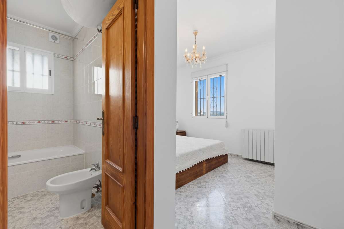 Bedroom with wooden door and access towards the bathroom inside a villa in Calpe.