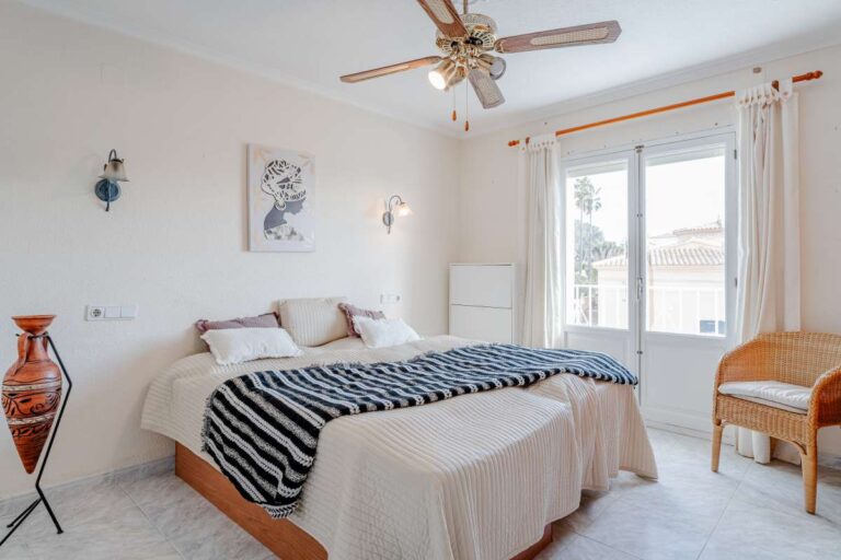 Bright bedroom with traditional furniture, ceiling fan and natural light inside a Mediterranean villa in Calpe.