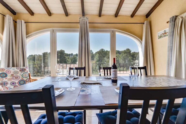 Bright dining area inside a charming Benissa Coast villa with large arched windows, beamed ceiling, dining table and natural light