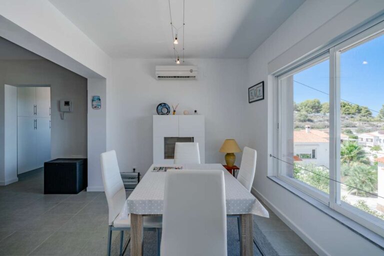 Bright dining area inside a modern villa in Calpe with large window and open views