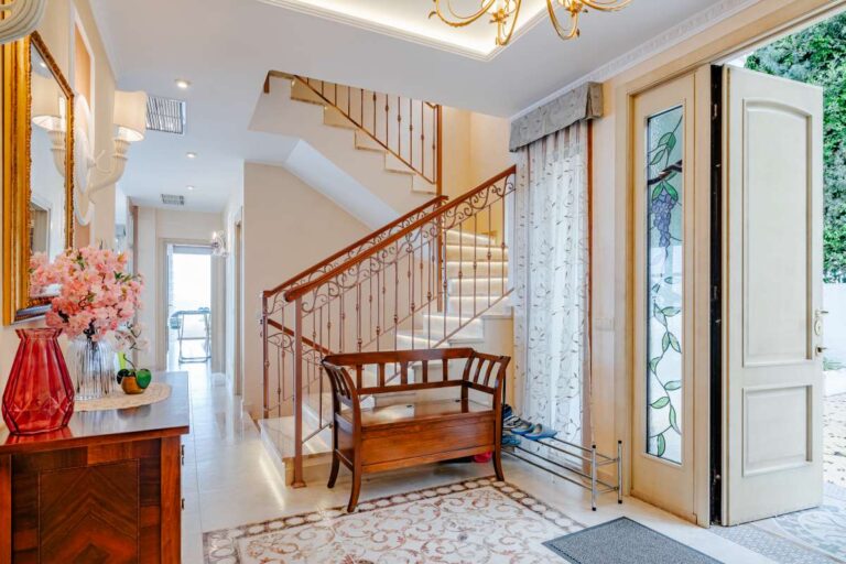 Bright entrance hall with staircase and traditional furniture inside a frontline villa in Les Bassetes, Benissa Coast.
