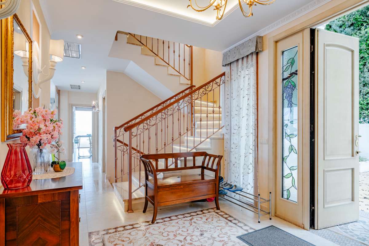 Bright entrance hall with staircase and traditional furniture inside a frontline villa in Les Bassetes, Benissa Coast.