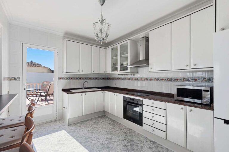 Bright fitted kitchen with window and appliances inside a villa in Calpe.