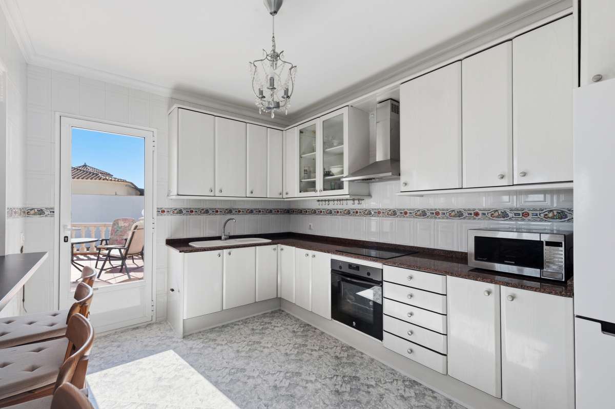 Bright fitted kitchen with window and appliances inside a villa in Calpe.