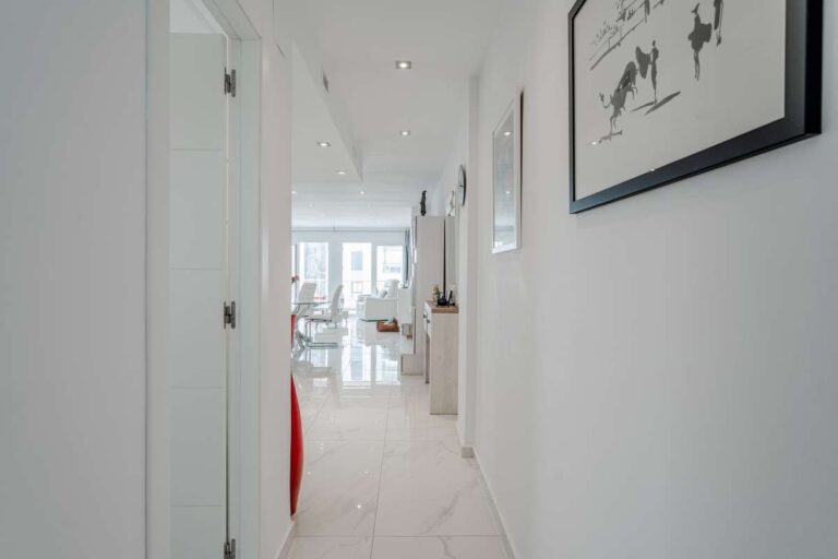 Bright hallway inside a renovated apartment by Arenal-Bol Beach in Calpe with modern white interior and access to the living area